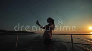 一个留着长发的漂亮女孩在她的智能手机上在<strong>河边</strong>、<strong>小</strong>山和天空前拍照