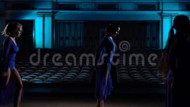 集体年轻的熟练芭蕾舞演员在大厅的舞台上跳现代芭蕾。 女生看礼堂。 着装
