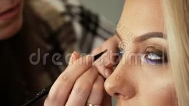 美容美发化妆师用一个金发碧眼的女人画眼睛上的阴影