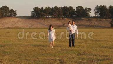 爸爸和小女儿，妈妈，在阳光下的田野里散步.. 孩子，爸爸和妈妈在阳光下的草地上玩耍