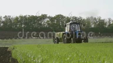 农用拖拉机在日落时用喷雾器、除草剂和杀虫剂在田间喷洒。 农用机械喷洒杀虫剂