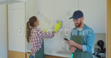男人和女人作为一个专业的清洁工，在厨房工作期间玩得很开心。