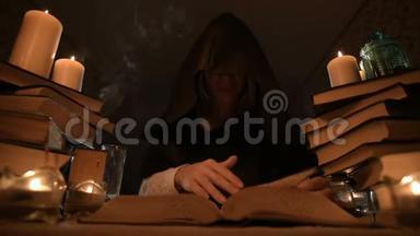 中等特写的女孩魔术师在一个黑暗的房间在烛光和寻找一个法术翻书。 低
