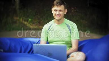 成熟的男人使用笔记本电脑，躺在公园的<strong>休息区</strong>，软泡芙上