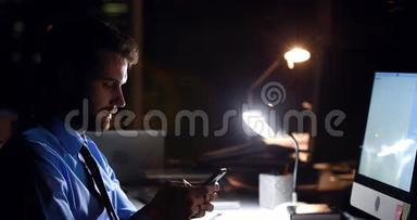 商务人员晚上使用智能手机和电脑
