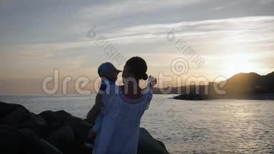 年轻的母亲把儿子抱在海边的<strong>怀里</strong>。