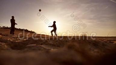 排球。 男子在沙滩剪影夕阳下打排球