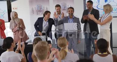 在一次商务会议上，男演讲者和鼓掌的观众和同事