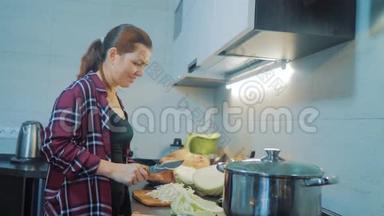 厨房里的女人准备一顿饭的概念。 厨房里的女孩用刀切卷心菜。 烹饪素食