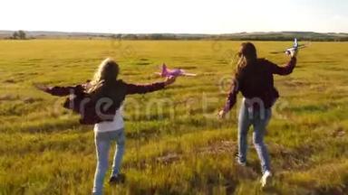 孩子们手里拿着飞机在草地上。 飞行的梦想。 快乐童年的概念.. 两个女孩玩