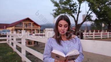 美丽的孕妇在农场读这<strong>本书</strong>。 她站在一旁看着书. 放松放松