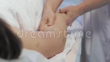 一位年轻女子在一家美容院做抗纤维素手按摩。 按摩师为年轻人做脂肪团按摩