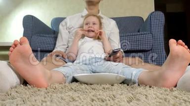 男人和女儿看电视，坐在地上吃零食