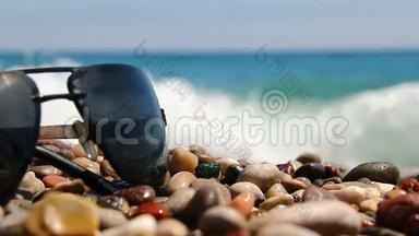 在海边的鹅卵石海滩上戴太阳镜。