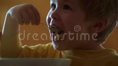 厨房里的孩子在桌子旁吃饭。 宝宝吃。 快乐的孩子。 宝贝在厨房吃食物。