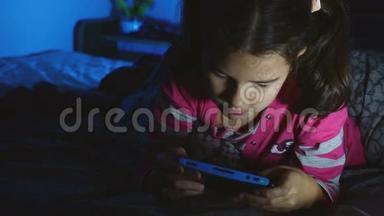 晚上在室内玩便携式电子游戏机的少女