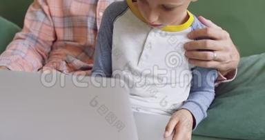 <strong>父亲和儿子在家里</strong>的沙发上用笔记本电脑