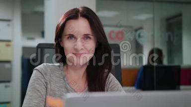 一位女士坐在办公室的笔记本电脑前