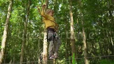一个穿着安全装备的小男孩爬上森<strong>林探</strong>险公园的一条路线。 他爬在高绳上. 室外