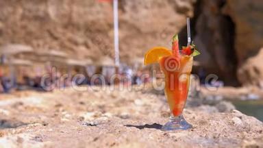 埃及海滩上的麦秆玻璃中的热带鲜榨果汁矗立在海边的岩石上