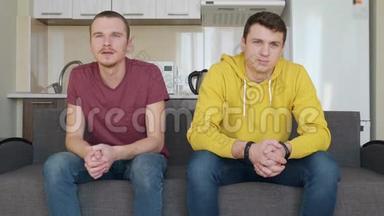 两个人坐在沙发上看足球赛