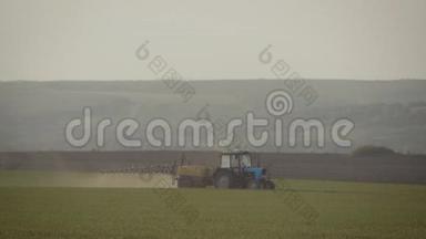 农用拖拉机在日落时用喷雾器、除草剂和杀虫剂在田间喷洒。 农用机械喷洒杀虫剂