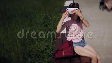 年轻女子在公园里使用头戴式显示器。 玩游戏使用VR头盔智能手机。 快乐