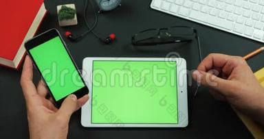 男人把绿色屏幕的智能手机放在绿色屏幕的桌子上