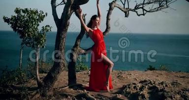 美丽的女人穿着红色的衣服在海边的悬崖上
