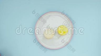 白色盘子中的甜色马卡龙或马卡龙在粉彩蓝色表面。