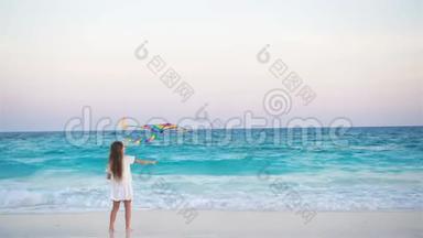 日落时在热带海滩放风筝的小女孩。 孩子在海边玩。 有沙滩玩具的孩子。