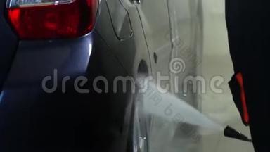 洗车机清洗汽车。 一个洗车工人用水洗一辆车。 特写镜头。