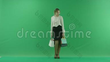 带着购物袋的漂亮购物女人。 女购物者拿着购物袋在绿色背景前的工作室。