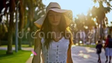 穿着白色裙子戴着帕梅拉帽子<strong>走路</strong>的漂亮女人