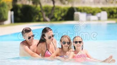 <strong>四人</strong>幸福的家庭在户外游泳池