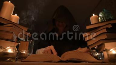 中等特写的女孩魔术师在一个黑暗的房间在烛光和寻找一个法术<strong>翻书</strong>。 低