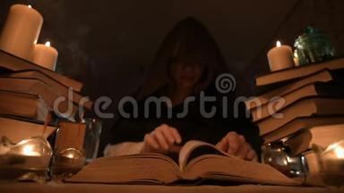 中等特写的女孩魔术师在一个黑暗的房间在烛光和寻找一个法术<strong>翻书</strong>。 低