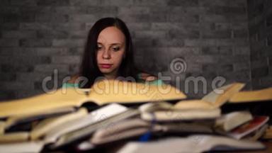 疲惫的女学生在<strong>书</strong>中读<strong>书</strong>。 一位身材魁梧的年轻女子坐在桌子旁，手里拿着一堆<strong>书</strong>，继续看<strong>书</strong>