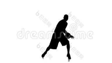 穿运动制服的篮球运动员塞球。 剪影。 慢动作