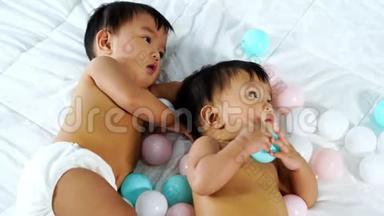 快乐的双胞胎宝宝在床上玩<strong>彩球</strong>