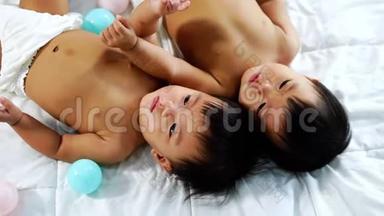 快乐的<strong>双胞胎宝宝</strong>在床上玩彩球