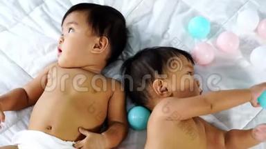 快乐的双胞胎宝宝在床上玩彩球