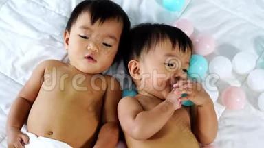 快乐的双胞胎宝宝在床上玩彩球
