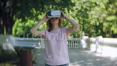 年轻女子在公园里使用头戴式显示器。 玩游戏使用VR头盔智能手机。 快乐