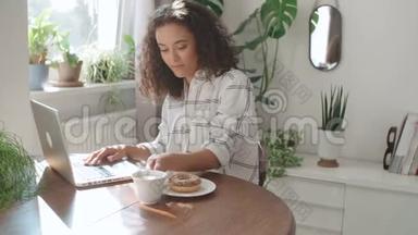 迷人的年轻女人在家里用笔记本<strong>电脑打字</strong>。