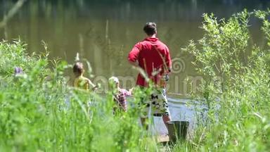 两个小孩和一个年轻的父亲在河岸钓鱼。 美丽的夏日风景。 户外娱乐活动。