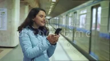 少女在地下<strong>地铁</strong>里乘<strong>地铁</strong>等待火车的到来，手持智能手机。 小女孩