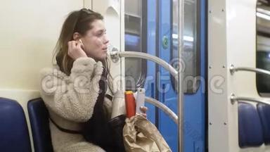 年轻的黑发女人乘坐<strong>公共交通工具</strong>，带着耳机使用电话