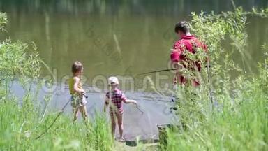 两个<strong>小孩</strong>和一个年轻的父亲在河岸钓鱼。 美丽的<strong>夏日</strong>风景。 户外娱乐活动。