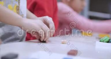 坐在书桌前的<strong>可爱</strong>的小孩子们在桌子上雕刻出了一与彩色<strong>造型</strong>塑料制成的不同的图形